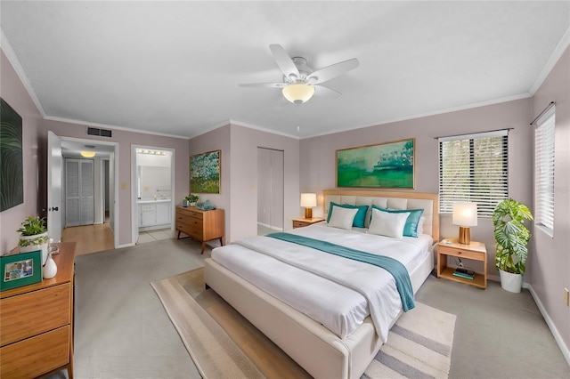 carpeted bedroom featuring ensuite bathroom, crown molding, ceiling fan, and a closet