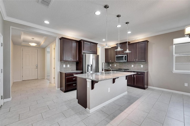 kitchen with pendant lighting, stainless steel appliances, a breakfast bar, a kitchen island with sink, and backsplash