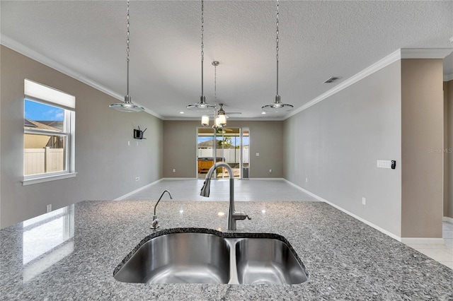 kitchen with crown molding, dark stone counters, a textured ceiling, and sink