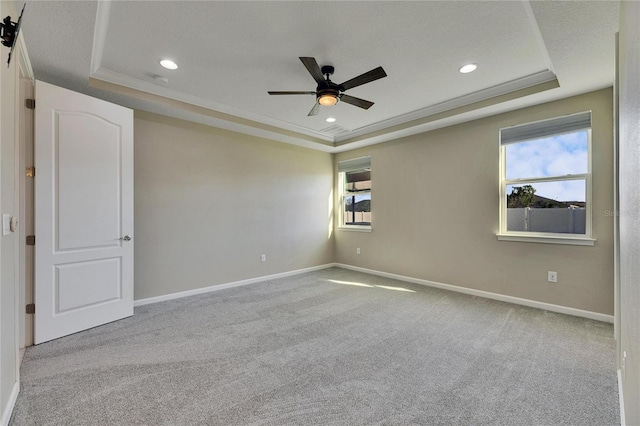 spare room featuring ceiling fan, a tray ceiling, and light carpet