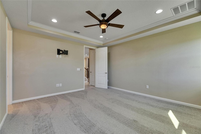 unfurnished room with light colored carpet, ceiling fan, a tray ceiling, and crown molding