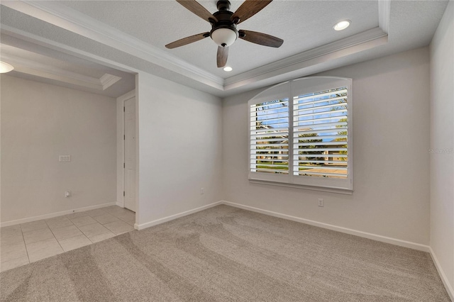 tiled empty room featuring a raised ceiling, a textured ceiling, ceiling fan, and ornamental molding