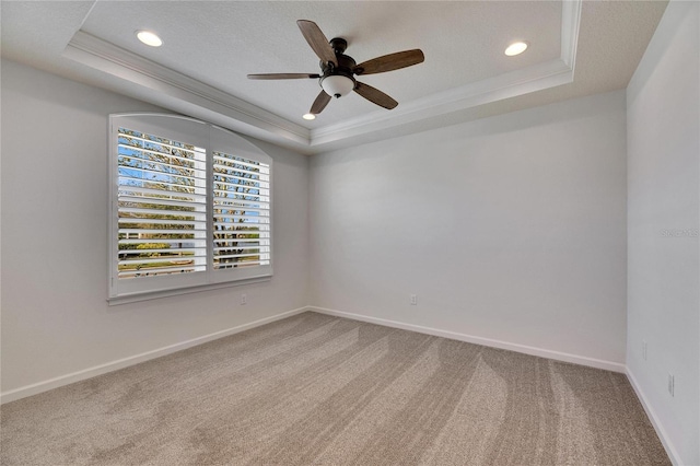 unfurnished room featuring ornamental molding, ceiling fan, a tray ceiling, and carpet