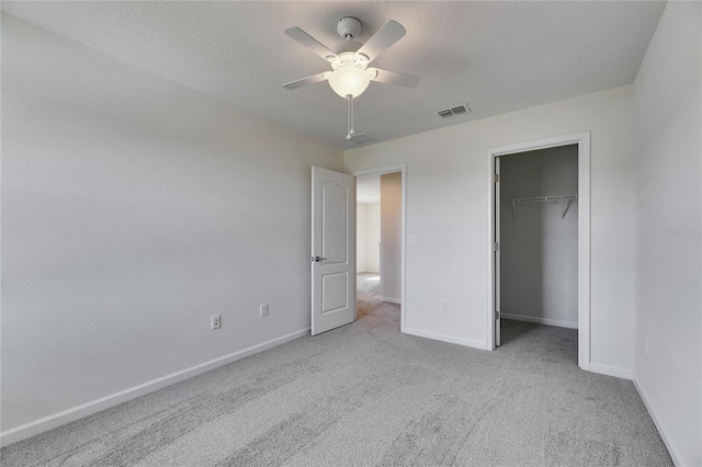 unfurnished bedroom with ceiling fan, a closet, light carpet, and a textured ceiling