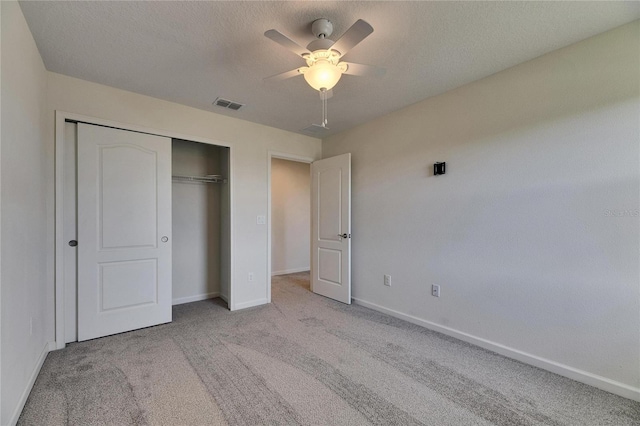 unfurnished bedroom with ceiling fan, a closet, light carpet, and a textured ceiling