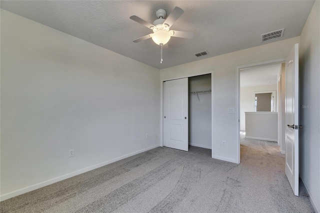 unfurnished bedroom featuring a closet, ceiling fan, a textured ceiling, and light colored carpet