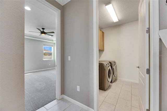 laundry room featuring a textured ceiling, light colored carpet, cabinets, washer and dryer, and ceiling fan