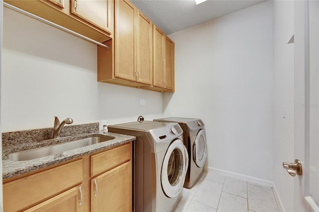 laundry room with cabinets, washer and dryer, light tile patterned floors, a textured ceiling, and sink