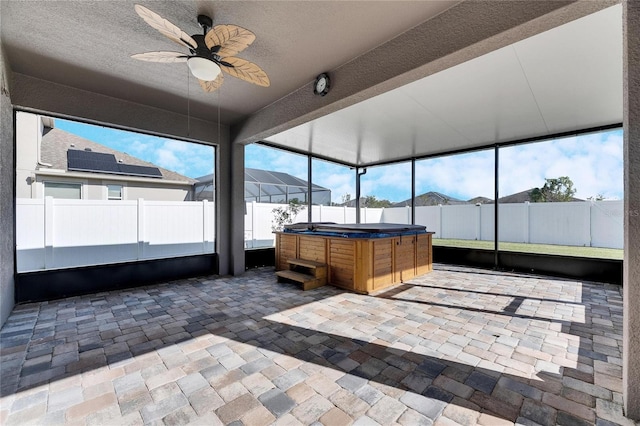 unfurnished sunroom with ceiling fan and a jacuzzi