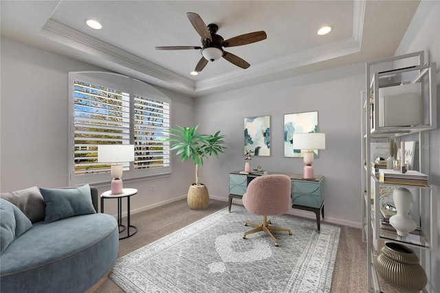 carpeted office space with a raised ceiling, ceiling fan, and ornamental molding