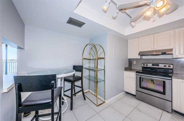 kitchen featuring decorative backsplash, a tray ceiling, ceiling fan, electric stove, and white cabinetry