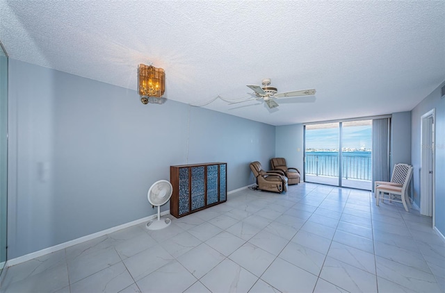 unfurnished room featuring a textured ceiling, a wall of windows, and ceiling fan