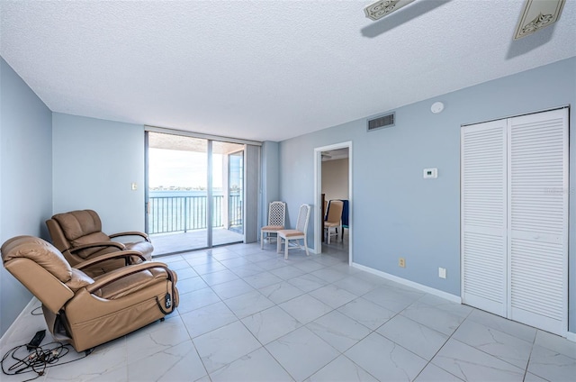 living area with floor to ceiling windows and a textured ceiling