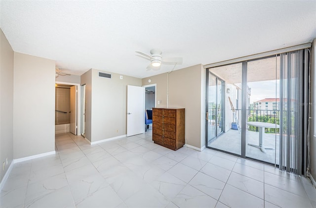 interior space with ceiling fan, access to outside, a textured ceiling, and connected bathroom