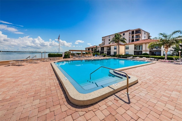 view of swimming pool featuring a water view and a patio area