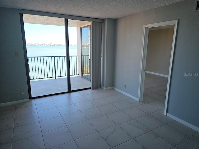 unfurnished room with visible vents, baseboards, a water view, expansive windows, and a textured ceiling