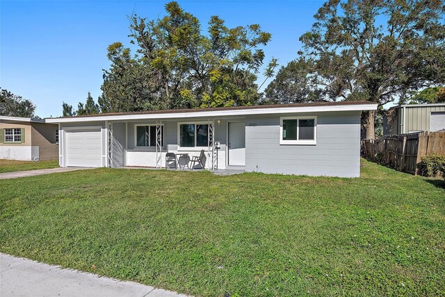 ranch-style house featuring a front lawn, fence, a garage, and driveway