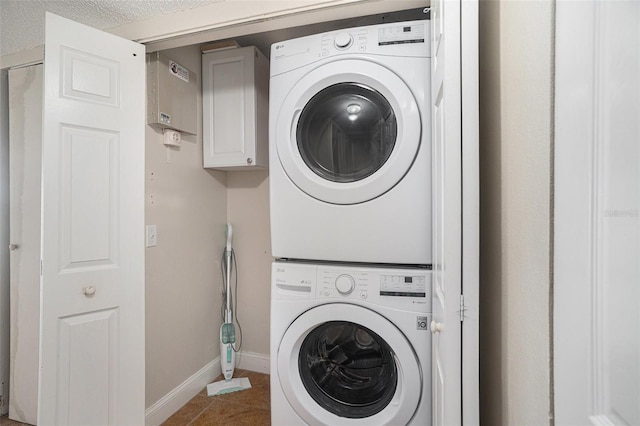 washroom featuring tile patterned floors, stacked washer / dryer, and a textured ceiling