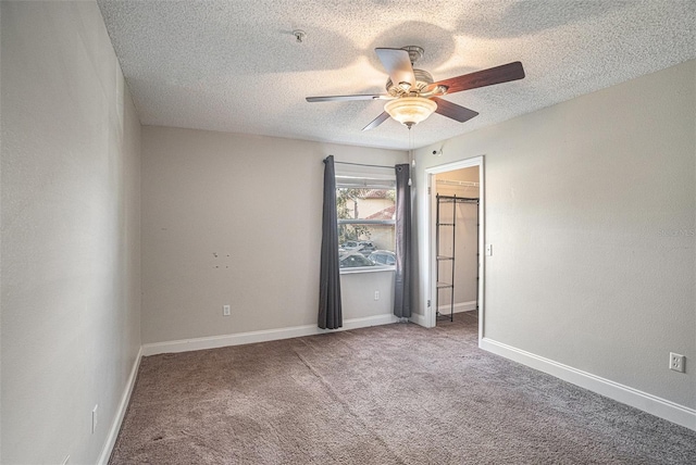 unfurnished bedroom featuring carpet flooring, ceiling fan, a textured ceiling, a walk in closet, and a closet