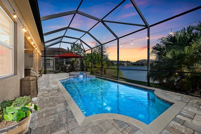 pool at dusk featuring a water view, a patio, glass enclosure, and an in ground hot tub