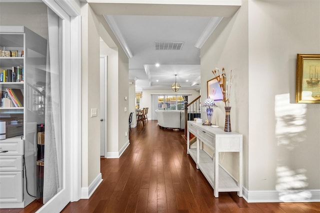 hallway with dark hardwood / wood-style floors, crown molding, and a notable chandelier