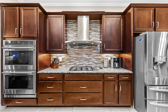 kitchen with wall chimney exhaust hood, stainless steel appliances, tasteful backsplash, light tile patterned flooring, and light stone counters