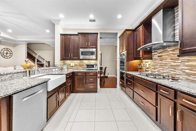 kitchen with light tile patterned flooring, sink, stainless steel appliances, ornamental molding, and wall chimney exhaust hood