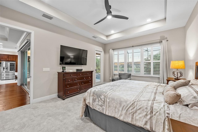 carpeted bedroom with ceiling fan, access to exterior, stainless steel fridge, and a tray ceiling