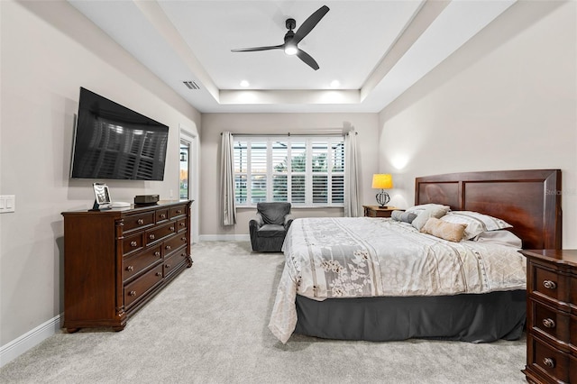 carpeted bedroom with ceiling fan and a tray ceiling