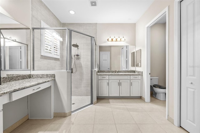 bathroom with toilet, vanity, tile patterned flooring, and a shower with door