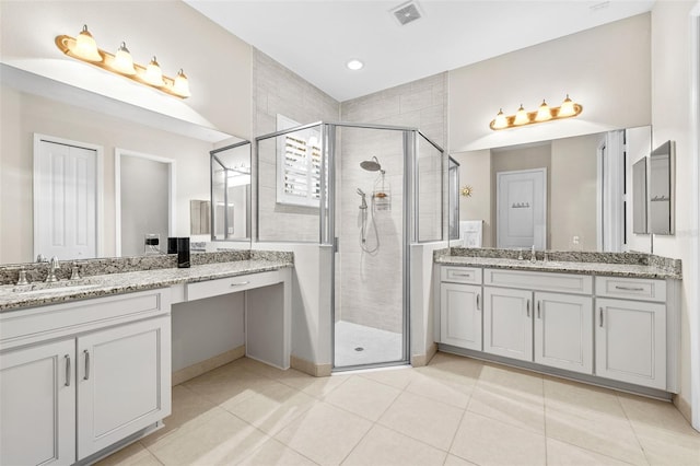 bathroom with a shower with shower door, vanity, and tile patterned flooring