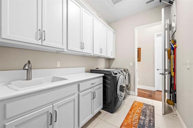 washroom with light tile patterned floors, sink, washing machine and clothes dryer, and cabinets