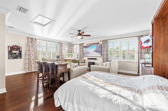 bedroom featuring ceiling fan, a fireplace, ornamental molding, and dark wood-type flooring