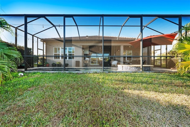 rear view of property with a lawn, a patio area, and glass enclosure