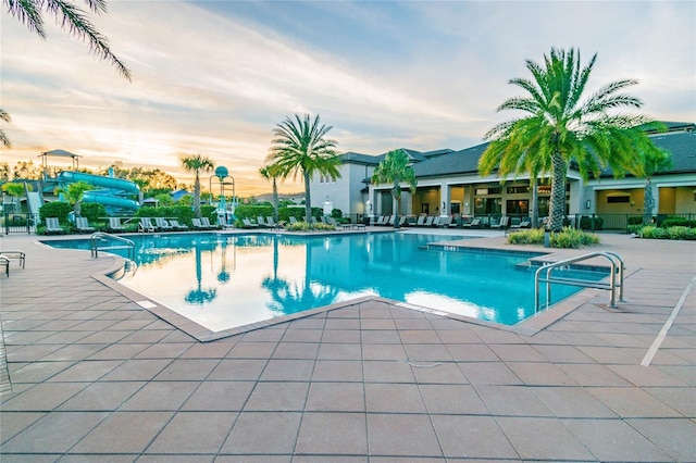 pool at dusk with a patio and a water slide