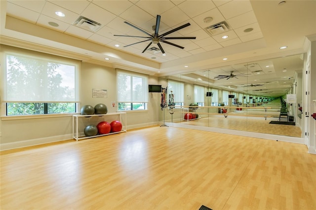 exercise area featuring ceiling fan, a tray ceiling, and light hardwood / wood-style floors