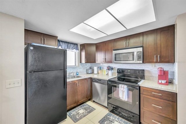 kitchen featuring tasteful backsplash, sink, light tile patterned floors, and black appliances