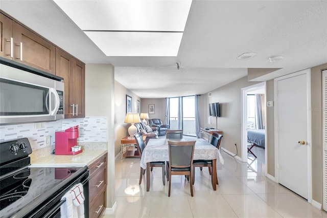 kitchen featuring decorative backsplash, light tile patterned floors, a textured ceiling, and black / electric stove