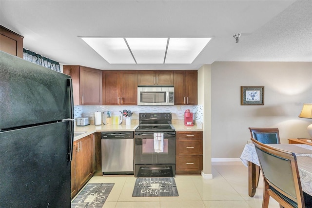 kitchen featuring light tile patterned flooring, backsplash, and black appliances