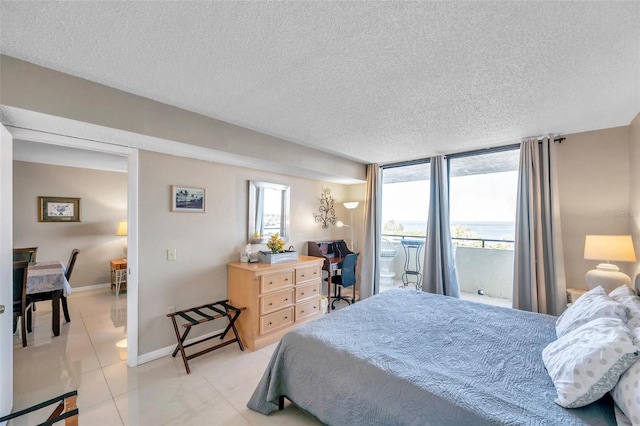 bedroom featuring light tile patterned flooring, a wall of windows, a textured ceiling, and access to outside