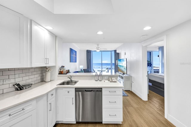 kitchen featuring kitchen peninsula, stainless steel dishwasher, ceiling fan, sink, and white cabinets