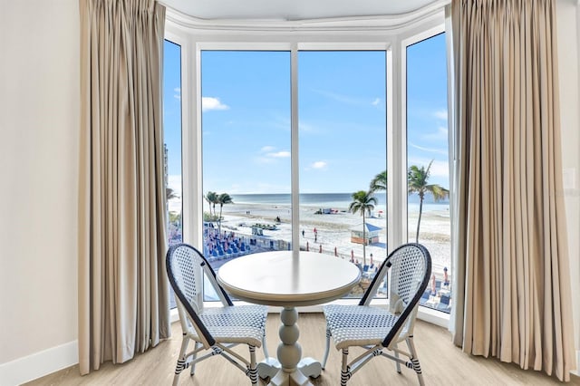 dining space with plenty of natural light, a water view, and a view of the beach