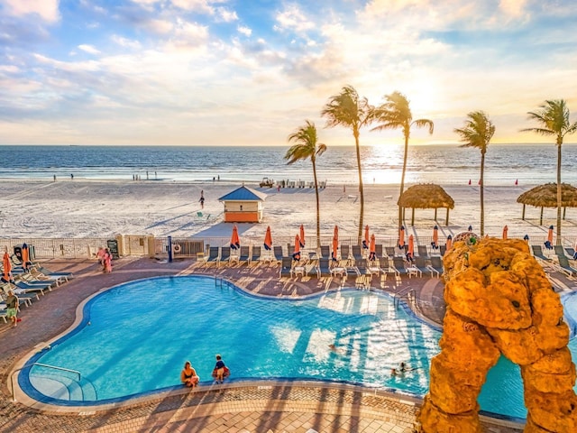 pool at dusk with a beach view and a water view