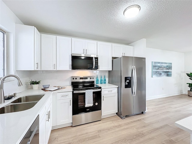 kitchen featuring appliances with stainless steel finishes, light hardwood / wood-style flooring, white cabinetry, and sink