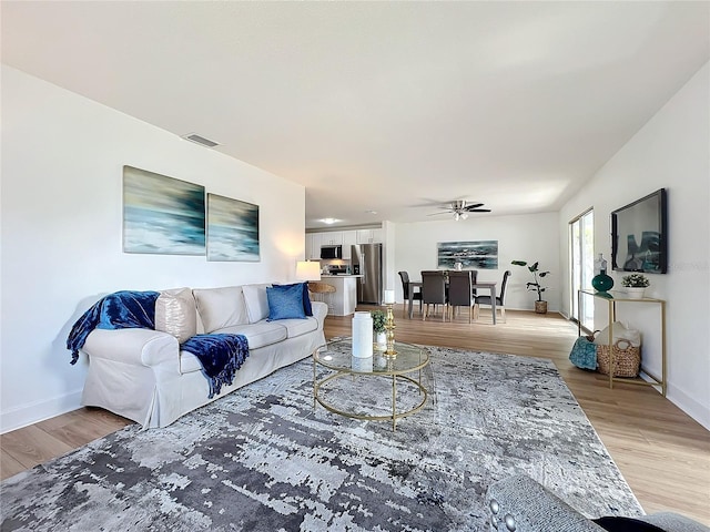 living room with ceiling fan and light hardwood / wood-style flooring