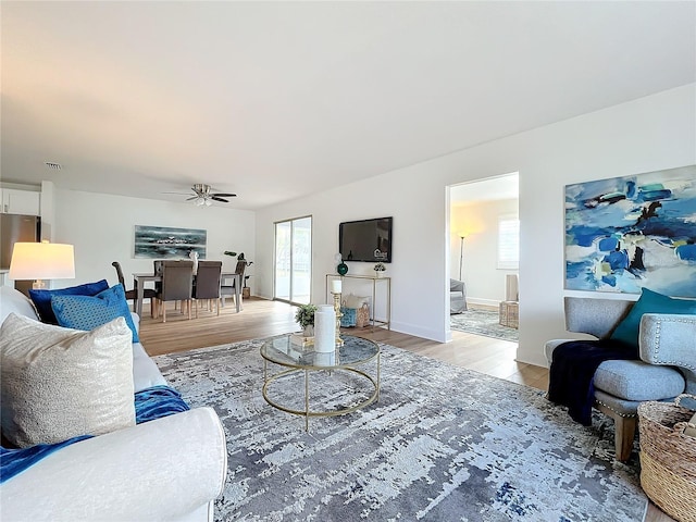 living room featuring a healthy amount of sunlight, ceiling fan, and light hardwood / wood-style floors