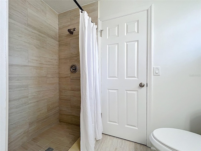 bathroom featuring a textured ceiling, toilet, and walk in shower