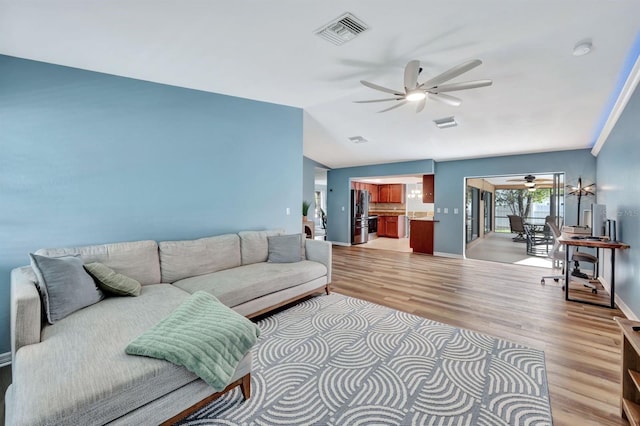 living room with ceiling fan, lofted ceiling, and light wood-type flooring