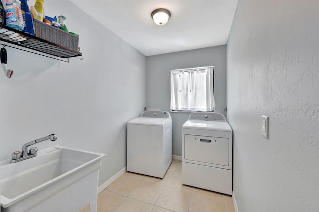 laundry area with light tile patterned floors, sink, and washing machine and clothes dryer