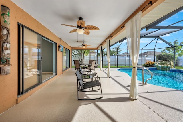 view of pool with glass enclosure, pool water feature, ceiling fan, and a patio